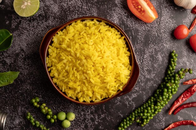 Foto arroz de cúrcuma en una taza marrón con especias en cemento negro