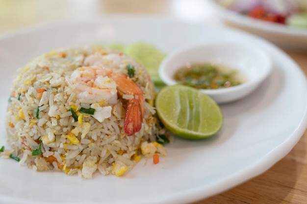 Arroz de camarão frito em um prato branco com molho de peixe pimentão em um copo