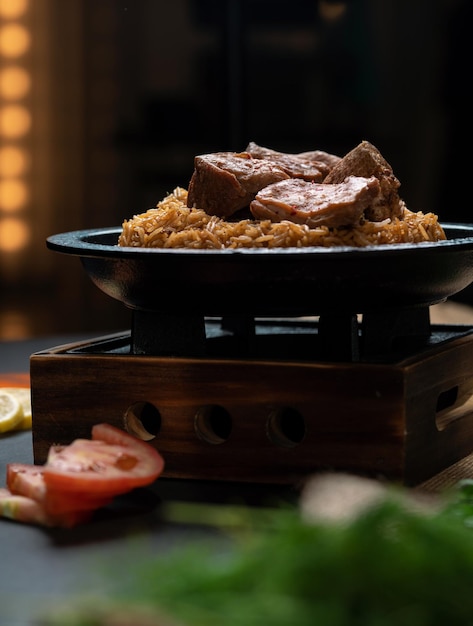 Arroz de carne É trazido e servido em um prato de pedra vista frontal