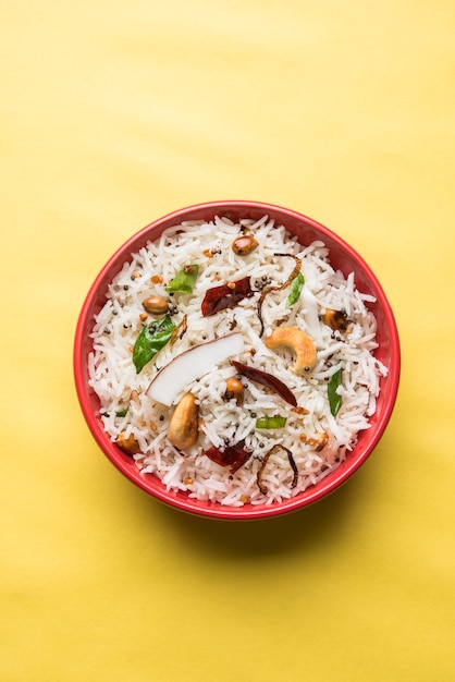 Arroz de coco - receita do sul da índia usando sobras de arroz basmati cozido, servido em uma tigela vermelha sobre um fundo sombrio, foco seletivo