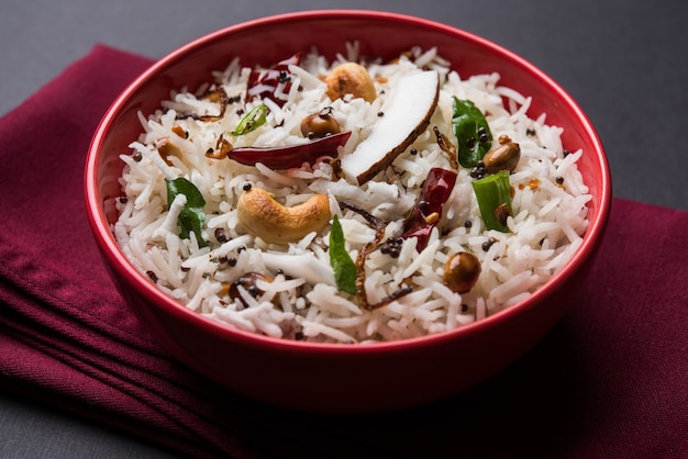 Arroz de coco - receita do sul da Índia usando sobras de arroz Basmati cozido, servido em uma tigela vermelha sobre um fundo sombrio, foco seletivo