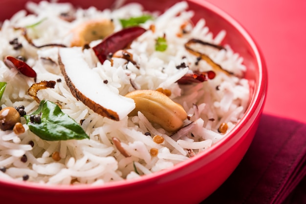 Arroz de coco - receita do sul da Índia usando sobras de arroz Basmati cozido, servido em uma tigela vermelha sobre um fundo sombrio, foco seletivo