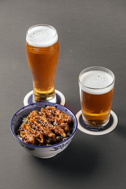 Arroz de frango Katsudon com cerveja em fundo cinza