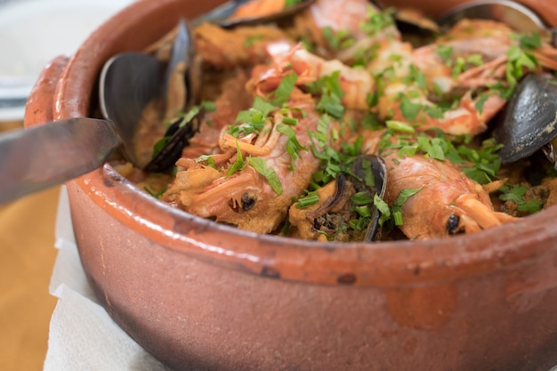 Arroz de frutos do mar em panela de cerâmica marrom em restaurante