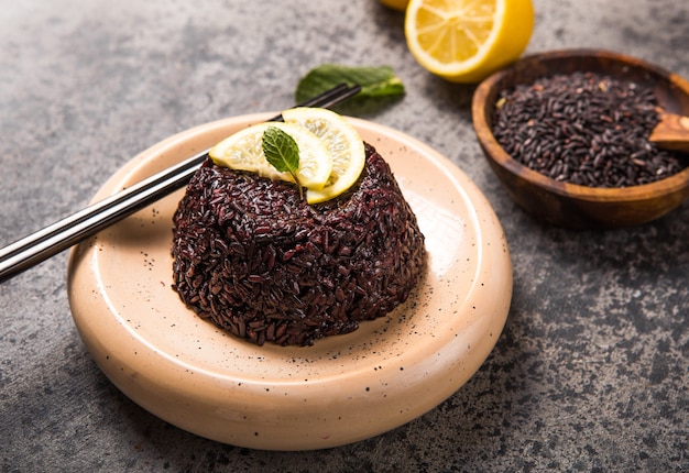 Arroz de jasmim preto tailandês cozido com sementes de chia, limão, gergelim sobre fundo cinzento concreto.