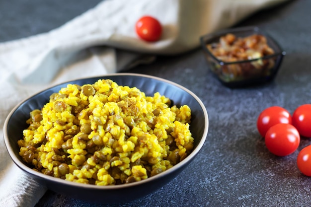 Arroz de lentilhas Mujadara e cebola frita em fundo escuro com têxteis leves