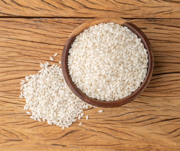 Arroz de risoto de carnaroli cru em uma tigela sobre a mesa de madeira