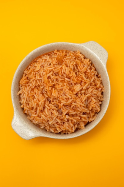 Arroz de tomate no prato em fundo amarelo