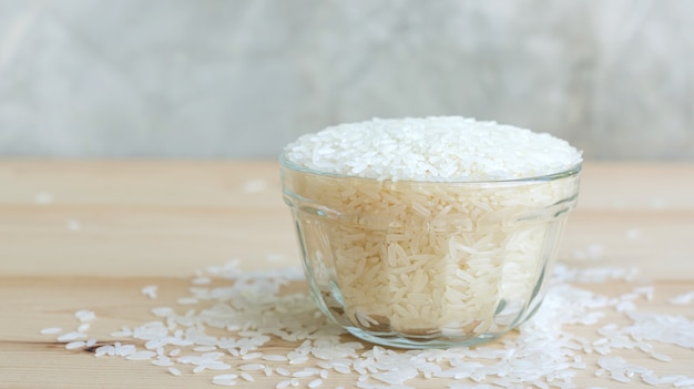 Arroz do jasmim em uma bacia em um fundo de madeira.