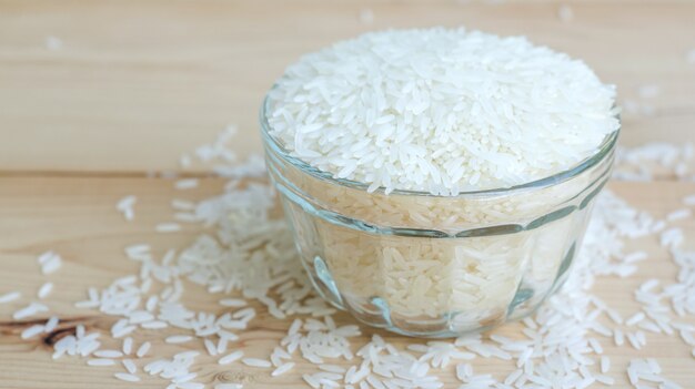 Arroz do jasmim em uma bacia em um fundo de madeira.