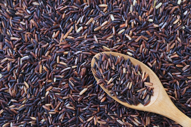 Arroz do jasmim na colher de madeira no fundo do arroz integral.