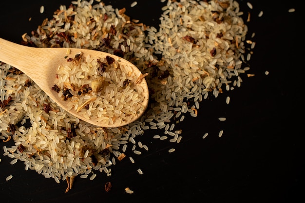 Arroz e colher de pau no fundo preto