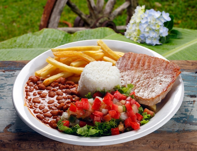 Arroz, frijoles, carne, patatas fritas y ensalada.