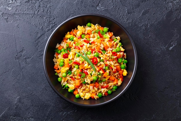 Arroz frito asiático con huevo y verduras Fondo de piedra oscura Vista superior