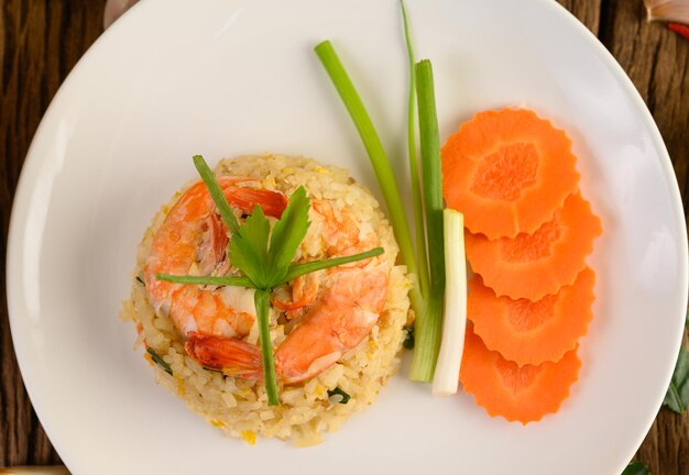 Arroz frito de camarón en un plato blanco en una mesa de madera