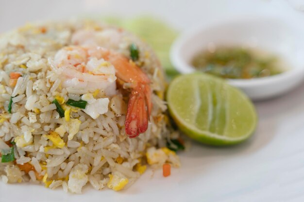 Arroz frito con camarones en un plato blanco con chile en salsa de pescado en una taza