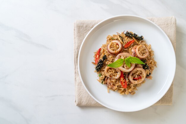 Arroz frito casero con albahaca y hierbas picantes con calamar o pulpo - estilo de comida asiática