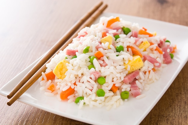 Arroz frito chinês com legumes e omelete na mesa de madeira