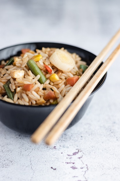 Arroz frito chinês e ovos servidos em uma tigela com pauzinhos. Cozinha chinesa