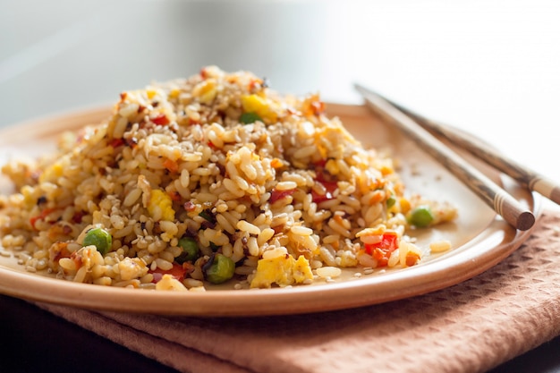 Arroz frito chino con verduras y huevos con palillos de cerca