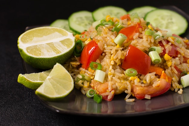 Arroz frito com khao pad kung asiático com vegetais, carne, ovo, pepino fresco e tomate