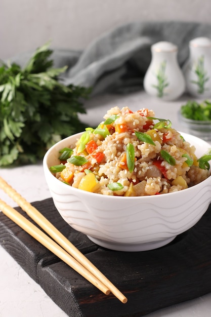 Arroz frito com legumes, alho, gengibre e cebola verde na mesa cinza. cozinha asiática. comida vegetariana. formato vertical