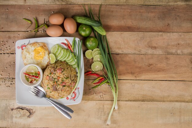 arroz frito com legumes, carne e ovos fritos, servidos em um prato com pauzinho