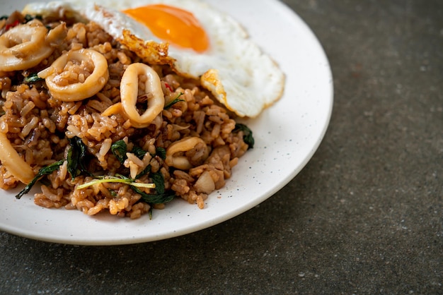 arroz frito com lula e ovo frito coberto de manjericão em estilo tailandês - estilo de comida asiática