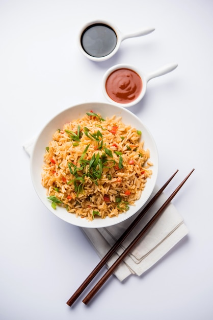 El arroz frito Schezwan Masala es una comida indochina popular que se sirve en un plato o tazón con palillos. enfoque selectivo