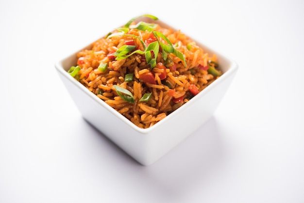 El arroz frito Schezwan Masala es una comida indochina popular que se sirve en un plato o tazón con palillos. enfoque selectivo