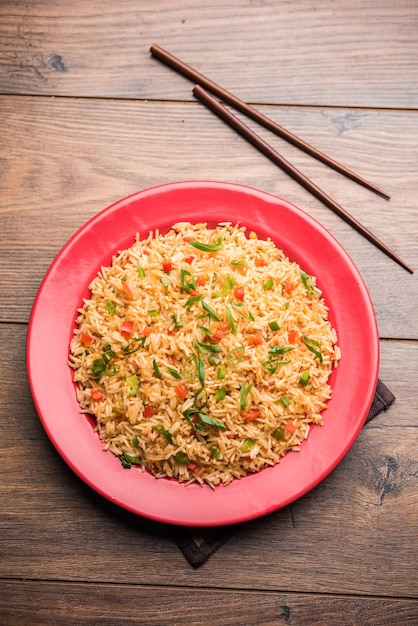 El arroz frito Schezwan Masala es una comida indochina popular que se sirve en un plato o tazón con palillos. enfoque selectivo