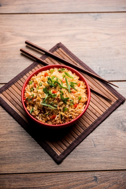 El arroz frito Schezwan Masala es una comida indochina popular que se sirve en un plato o tazón con palillos. enfoque selectivo