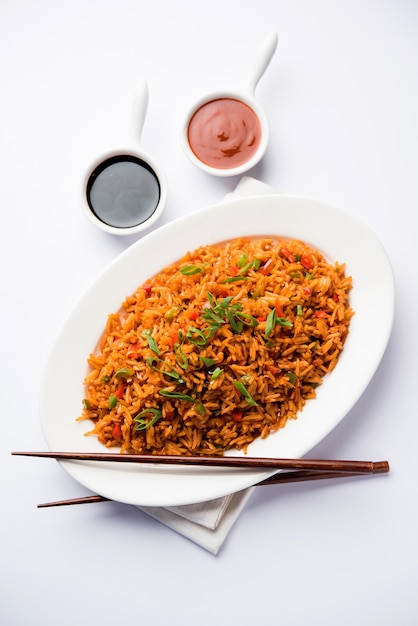 El arroz frito Schezwan Masala es una comida indochina popular que se sirve en un plato o tazón con palillos.