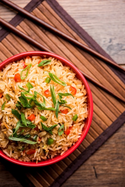 El arroz frito Schezwan Masala es una comida indochina popular que se sirve en un plato o tazón con palillos.
