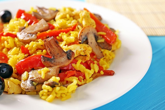 Arroz frito con verduras en plato sobre mesa de madera azul