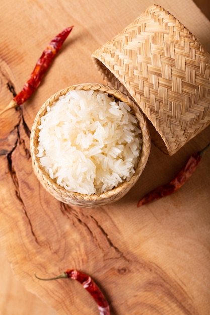 Arroz glutinoso o pegajoso de la comida asiática asiática en el mimbre de bambú en fondo de madera con el espacio de la copia