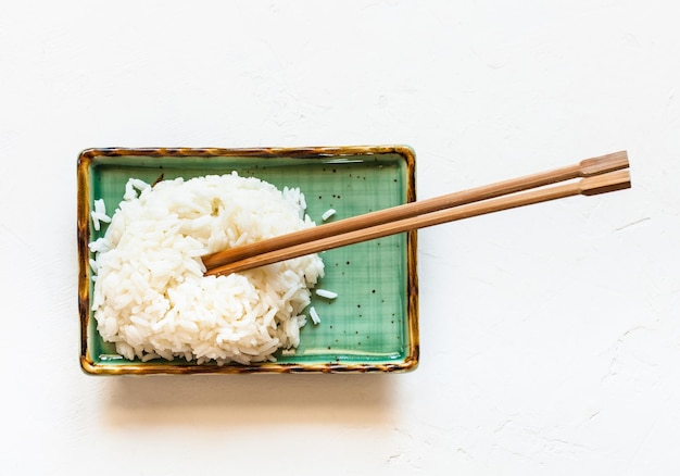 Arroz hervido con palillos en un plato en blanco