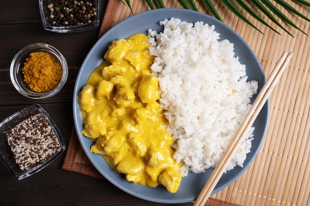 Arroz hervido con pollo en salsa de curry en un plato azul y servilleta de bambú