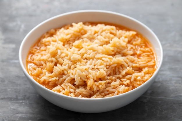 Arroz hervido con tomate en un recipiente sobre la mesa de cerámica