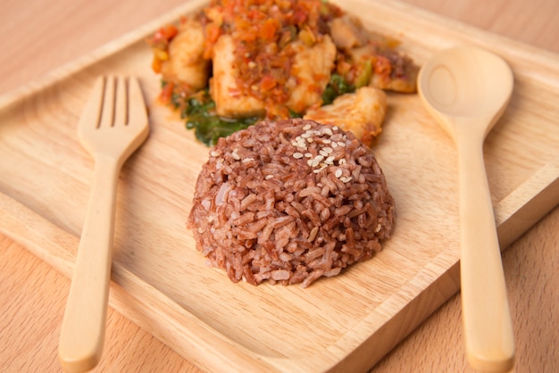 Arroz integral com pasta picante frito com peixe em prato de madeira