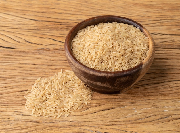 Arroz integral cru em uma tigela sobre a mesa de madeira