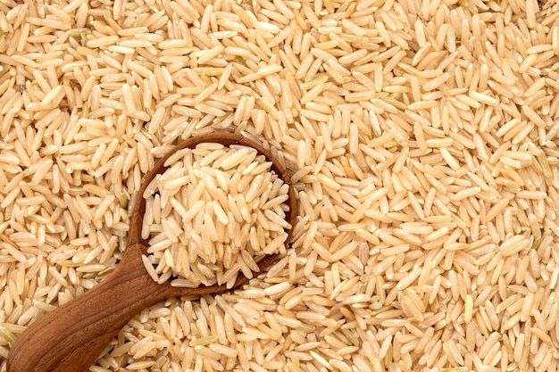 Arroz integral em uma colher de pau no fundo de sementes de arroz