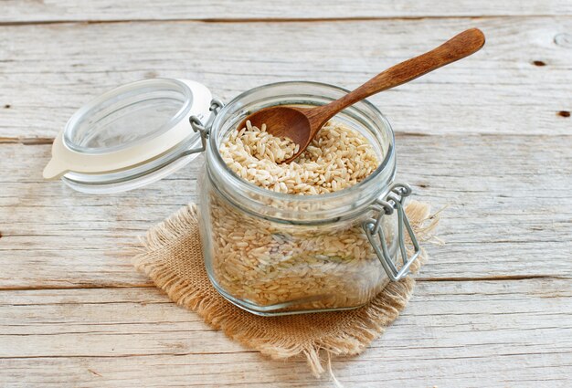 Arroz integral en un vaso con una cuchara sobre fondo de madera