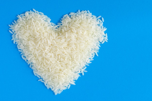 Arroz de jazmín en forma de corazón sobre fondo azul.