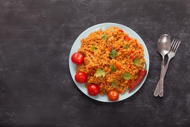 Arroz jollof con perejil en un plato sobre fondo negro. Cocina nacional de África.