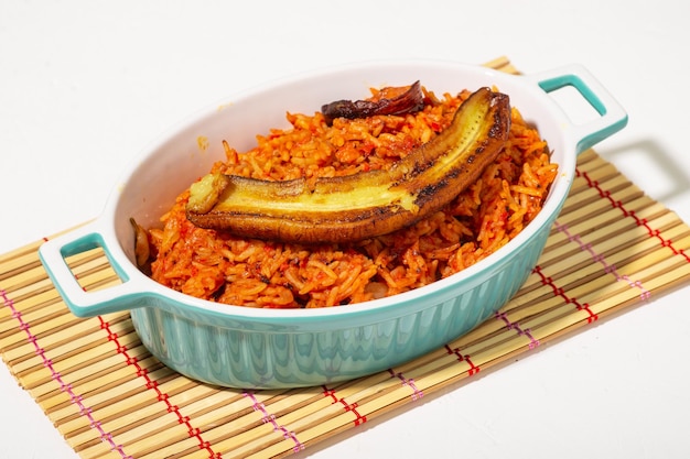 Arroz jollof con plátano frito Comida tradicional de arroz nigeriano con tomates, cebollas y especias Fondo claro