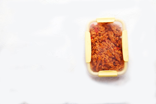 Arroz jollof vegetariano con carne de soja en una lonchera transparente sobre un fondo blanco Copiar spaes