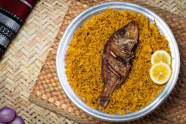 Arroz kabsa de peixe sheri árabe com fatia de limão servido na vista superior do prato de comida do oriente médio