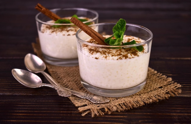 Arroz con leche con canela en vasos sobre un fondo de madera oscura.