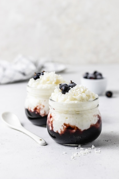 Foto arroz con leche de postre saludable con mermelada de arándanos en frascos de vidrio.